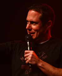 Jonathan McKee holding a microphone on stage.